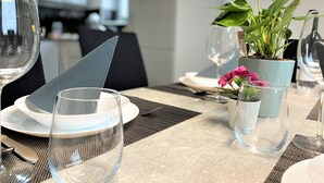 A dining table set with plates, glasses, and a potted plant with flowers. - LUXURY Apartment 2 floors 3BR! +NETFLIX +HIGH-END (Ližnjan)