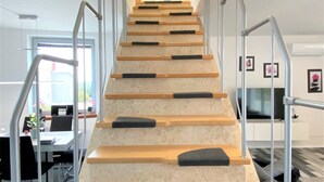 A modern staircase with wooden steps and black non-slip treads, leading to a landing with a glass door. - LUXURY Apartment 2 floors 3BR! +NETFLIX +HIGH-END (Ližnjan)