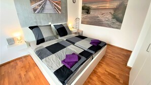 A bedroom with a bed, two nightstands, a wall clock, and two paintings of a sunset over a beach. - LUXURY Apartment 2 floors 3BR! +NETFLIX +HIGH-END (Ližnjan)