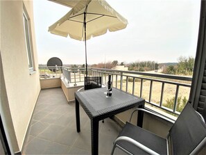 A balcony with a table, chairs, and a wine bottle.