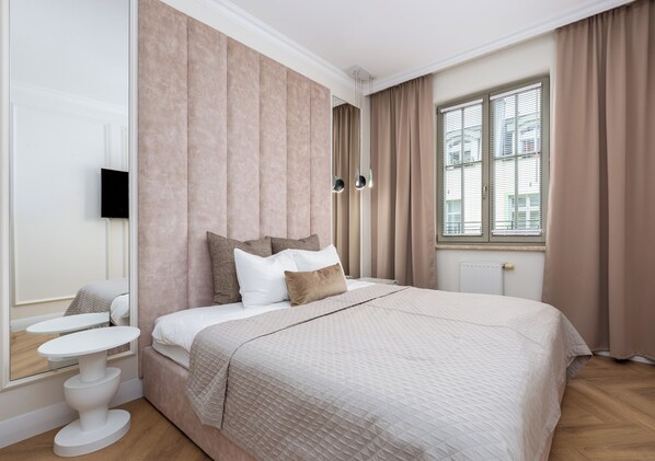 Ein Schlafzimmer mit einem großen Bett, einem Nachttisch, einem Spiegel und einem Fenster mit Vorhängen.