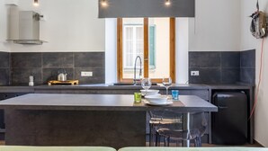 A modern kitchen with a central island, dark tiles, and pendant lighting. - GuestHost - Little Venice Charming Flat with Canal View (Livorno)