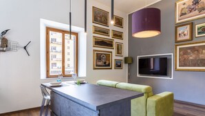 A modern kitchen with a central island, a dining area with a green sofa, and a TV mounted on the wall. - GuestHost - Little Venice Charming Flat with Canal View (Livorno)