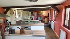 A modern kitchen with a central island, wooden beams, and a red accent wall. - LONGERE NEAR HONFLEUR, DEAUVILLE, LE HAVRE (Beuzeville)