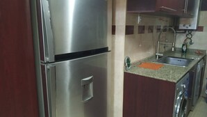 Una cocina con electrodomésticos de acero inoxidable, un lavamanos y una lavadora.