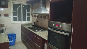 Una cocina con estufa a gas, horno y ventana con marco decorativo.