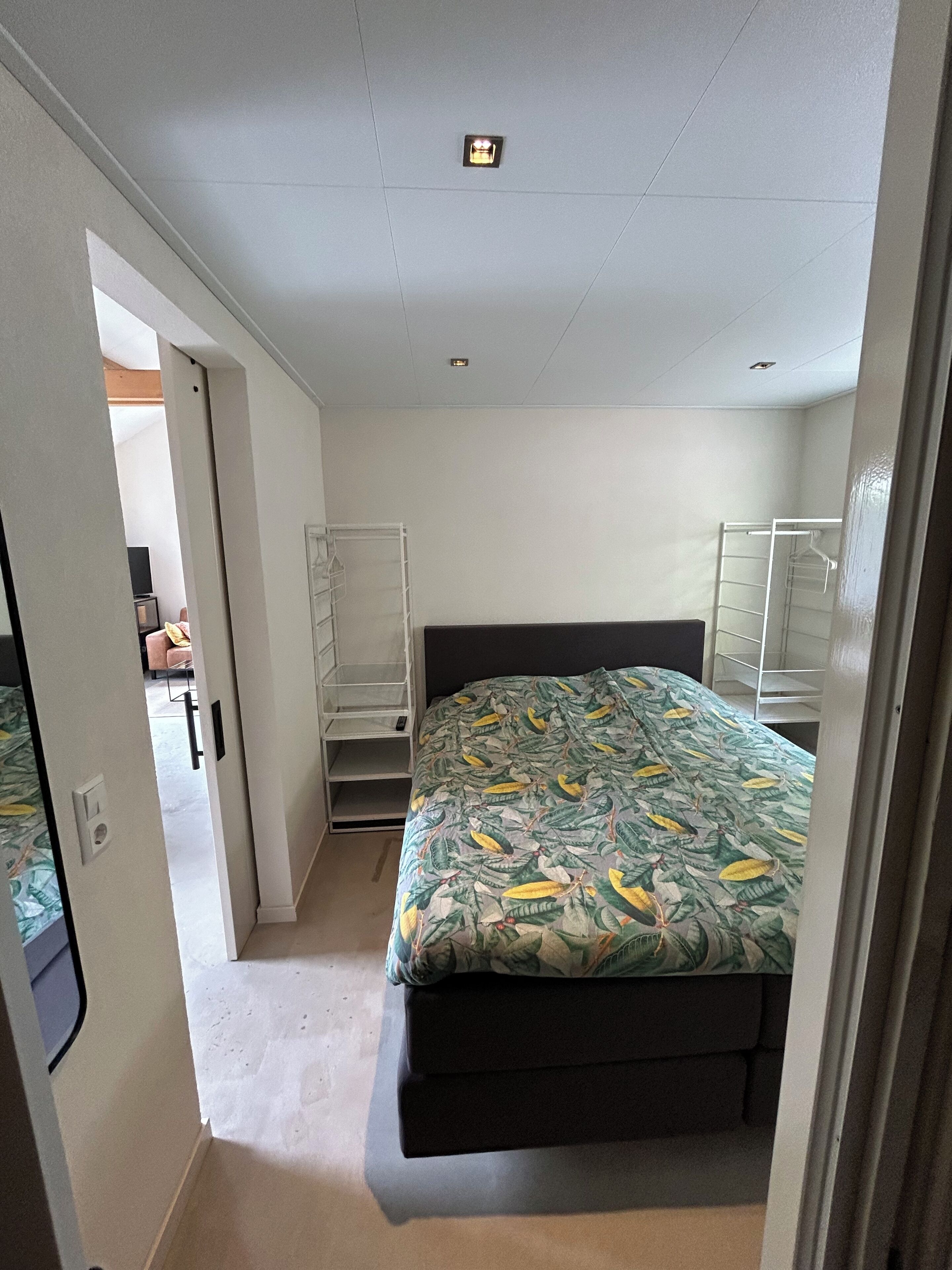 A bedroom with a bed, a wardrobe, and a shelving unit.