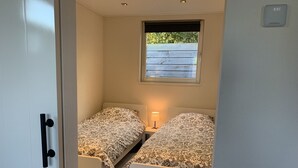 Una habitación pequeña con dos camas, una ventana y un termostato.