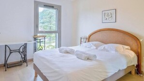 Un dormitorio con una cama grande, una ventana, un escritorio y una silla.