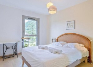 Ein Schlafzimmer mit Bett, Schreibtisch, Stuhl und Fenster.