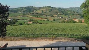 Un balcón con vistas a ondulantes colinas verdes y un cielo despejado.