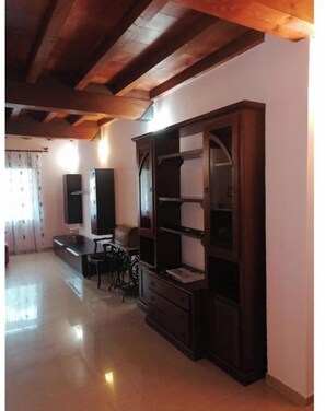 Amplia sala de estar con techo de madera, estantería empotrada y zona de comedor con mesa y sillas.