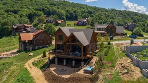 Un ensemble de chalets en bois dotés d’un bain à remous et d’une terrasse, entourés d’une végétation luxuriante et de collines.