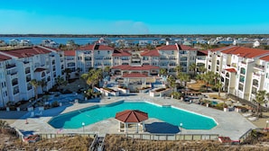 Un resort con varias construcciones, una piscina central y vista al océano.