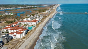 Un hotel frente al mar con varias edificaciones, una playa y un muelle.
