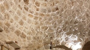 Una habitación con techo de piedra, una cama con dosel y una pequeña mesa.