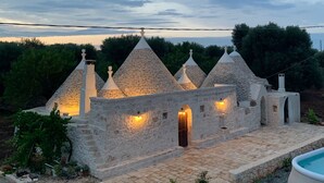 Un edificio de piedra con varios techos cónicos, una piscina y un jardín.
