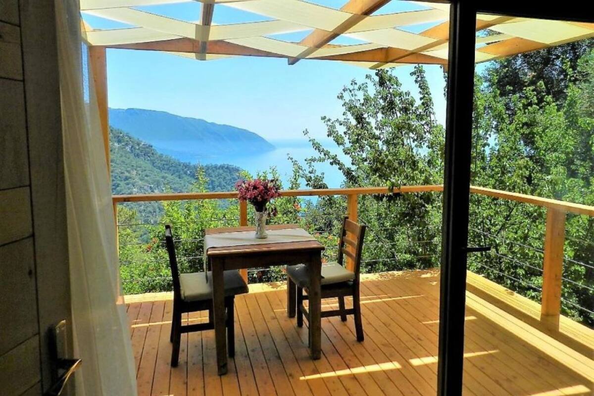 A wooden deck with a table and chairs, overlooking a mountainous landscape.