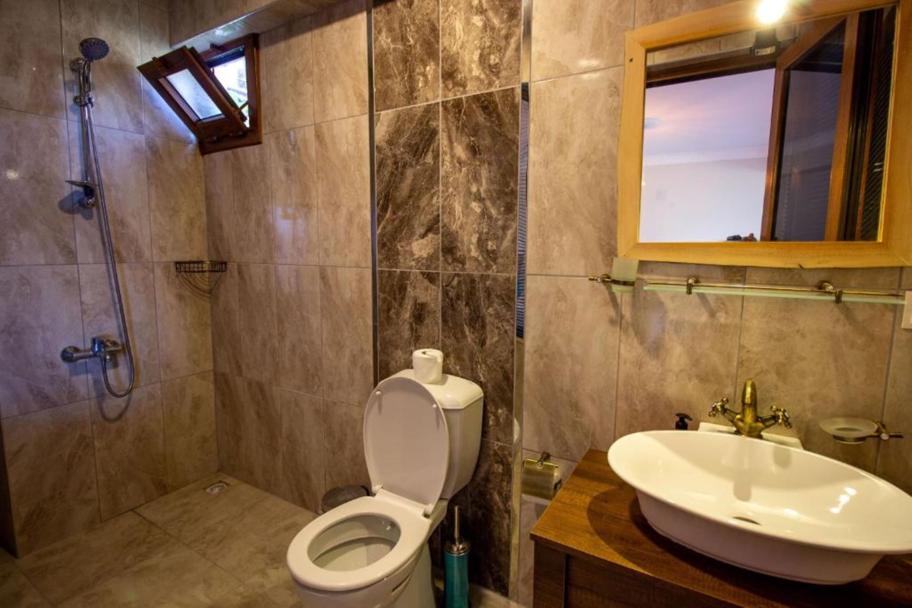 A bathroom with a toilet, shower, and sink.