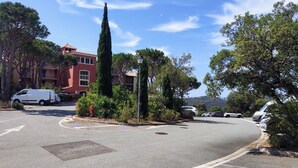 A residential area with a red building, parked cars, and a fire hydrant. - Residence LE HAMEAU DES ISSAMBRES (Les Issambres)