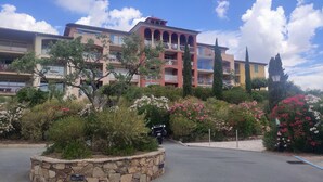 A multi-story hotel with balconies, surrounded by landscaped gardens and cypress trees. - Residence LE HAMEAU DES ISSAMBRES (Les Issambres)