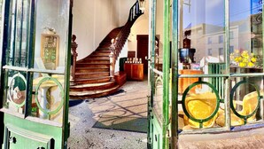 Una escalera conduce a un segundo piso, un mostrador de recepción y vistas de la calle a través de amplias ventanas.
