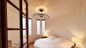 Un dormitorio con una cama grande, una mesita de noche, una silla y una ventana con vistas.