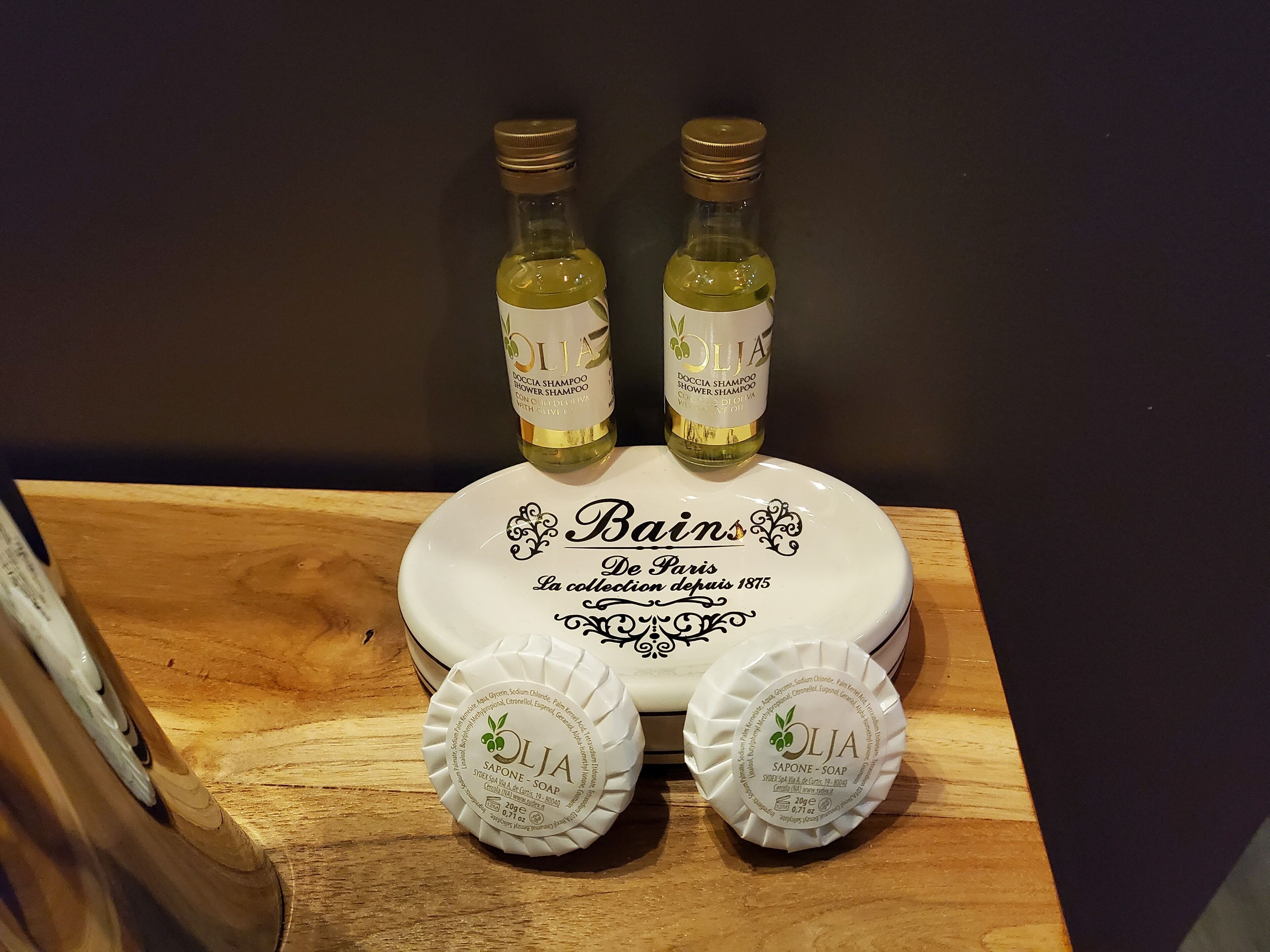 Un plateau en bois avec deux bouteilles d’huile d’olive et deux savons.