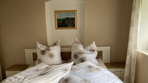 Un lit bien fait, avec une couette à motifs floraux, une tête de lit et un tableau accroché au-dessus.