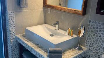 A bathroom with a rectangular sink, a wooden-framed mirror, and a towel rack.