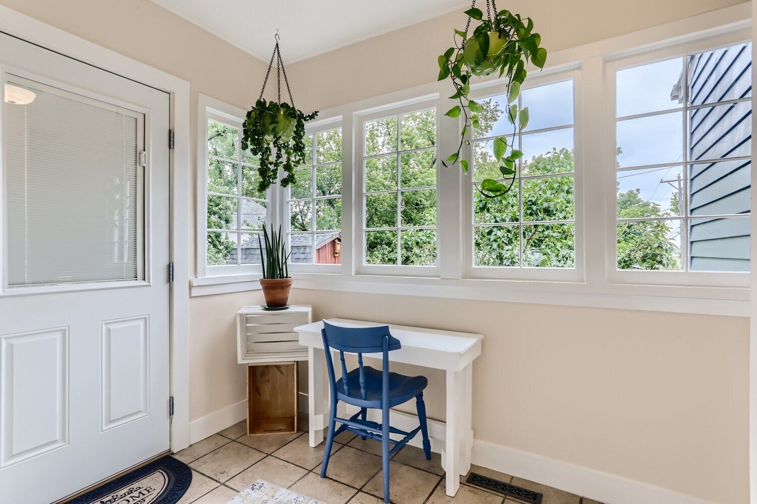 A room with a white desk, a blue chair, and a potted plant on a windowsill.