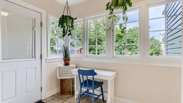 A room with a white desk, a blue chair, and a potted plant on a windowsill.