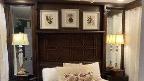 A bedroom with a bed, two nightstands, a ceiling fan, and framed botanical prints on the wall. - Downtown Boyne City. Great Backyard  (Boyne City)