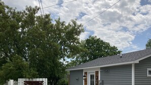 A single-story building with a gravel driveway, a white picket fence, and a mailbox. - Downtown Boyne City. Great Backyard  (Boyne City)