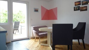 A modern interior with a wooden floor, a round table, two chairs, a large window, and a ceiling light.
