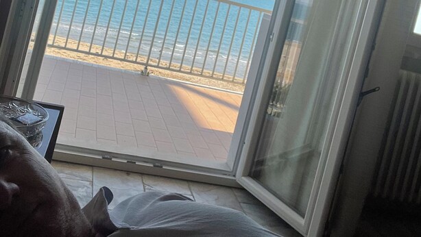 Ein Zimmer mit einer großen Schiebetür und Blick auf einen Strand.