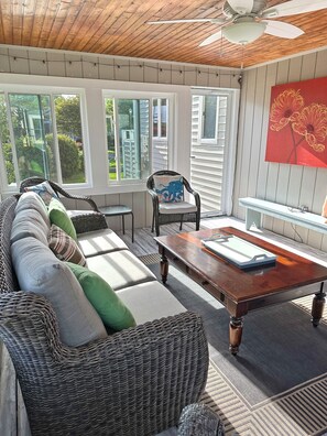 Une pièce lumineuse, avec un canapé, des fauteuils, une table et de grandes fenêtres.