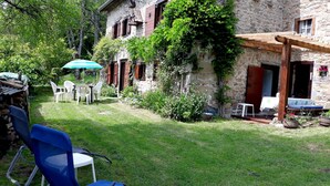A stone building with a garden patio, outdoor seating, and a wooden pergola. - Maison Campagnarde ,parc Clôturé,altitude 1025m (Saint Pierre La Bourlhonne)