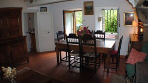 A dining area with a wooden table and chairs, a chandelier, and a view of greenery through a window. - Maison Campagnarde ,parc Clôturé,altitude 1025m (Saint Pierre La Bourlhonne)