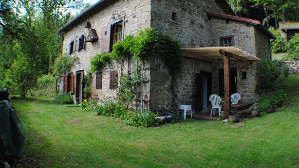 A stone house with a covered porch, a small garden, and two white chairs outside. - Maison Campagnarde ,parc Clôturé,altitude 1025m (Saint Pierre La Bourlhonne)