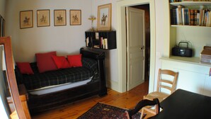 A cozy living room with a plaid sofa, a bookshelf, and framed pictures on the wall. - Maison Campagnarde ,parc Clôturé,altitude 1025m (Saint Pierre La Bourlhonne)