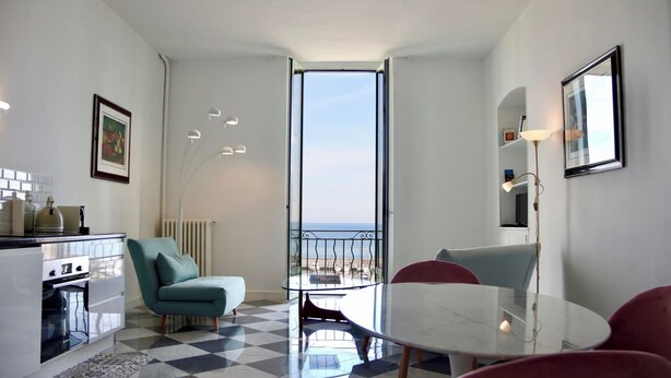 Una cocina moderna con piso de tablones, un comedor con mesa de vidrio y un balcón con vistas.