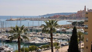 Un puerto deportivo con barcos, palmeras y una vista distante de edificios.