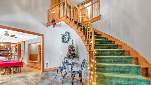 A staircase with a wooden railing and green carpeted steps, leading to an upper floor.