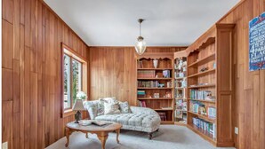A cozy room with wooden walls, a comfortable sofa, a coffee table, and a bookshelf filled with books.