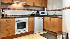 Een keuken met houten kastjes, een roestvrijstalen oven, een magnetron en een vaatwasser.