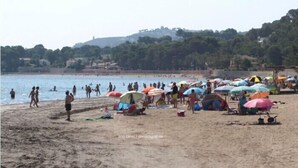 Een strand met mensen, parasols en tenten.