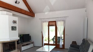 Una sala de estar con chimenea, un sofá, un televisor y un comedor con mesa y sillas.