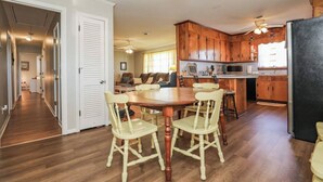A spacious kitchen with wooden cabinets, a dining area with a wooden table and chairs, and a visible refrigerator. - Sneads Ferry 4BR Waterfront Home Near Camp Lejeune (Sneads Ferry)