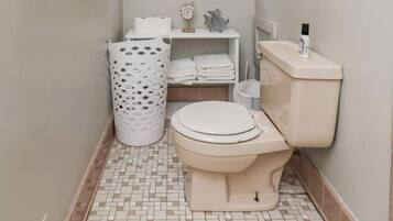 Une petite salle de bain comprenant des toilettes, un lavabo, une fenêtre et une poubelle.